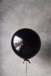 grayscale photography of balloon beside chanel metal barrel